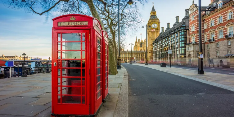 Red telephone boxes on a London street with Big Ben and the Houses of Parliament in the background
